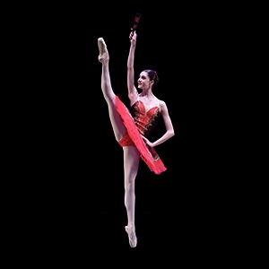 Ballet dancer in red tutu extending right leg in air